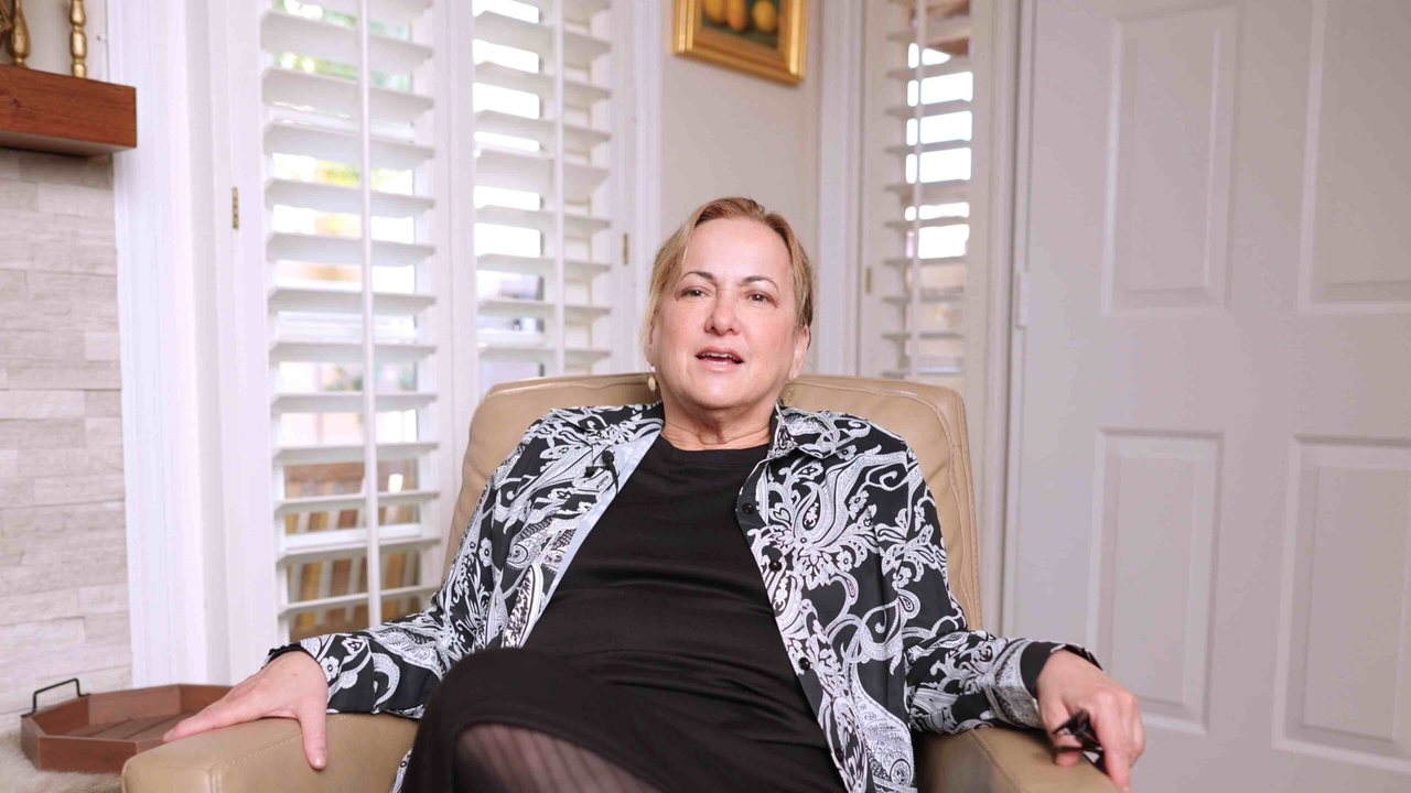 Ayala Weinberg seated in her living room during her filmed testimonial